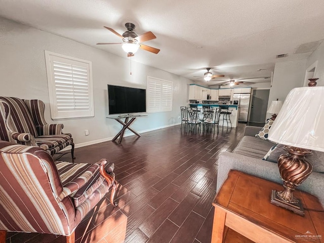 living room with a textured ceiling, dark hardwood / wood-style floors, and ceiling fan