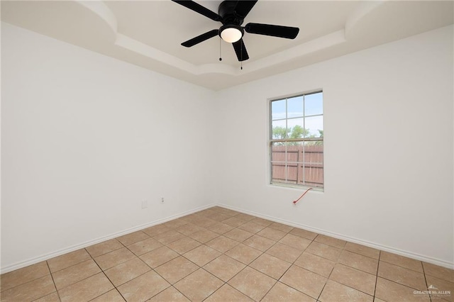 tiled spare room with ceiling fan and a raised ceiling