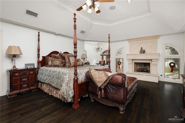 bedroom with ceiling fan, a large fireplace, wood-type flooring, and a tray ceiling