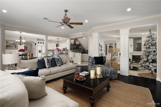 living room featuring ceiling fan with notable chandelier, wood-type flooring, and crown molding