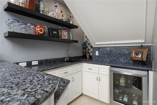 bar with white cabinetry, sink, beverage cooler, dark stone counters, and decorative backsplash