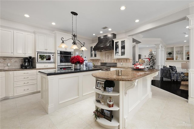 kitchen with pendant lighting, kitchen peninsula, decorative backsplash, appliances with stainless steel finishes, and custom range hood