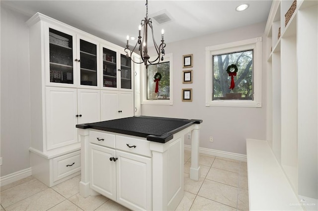 kitchen featuring pendant lighting, a center island, white cabinetry, and light tile patterned floors