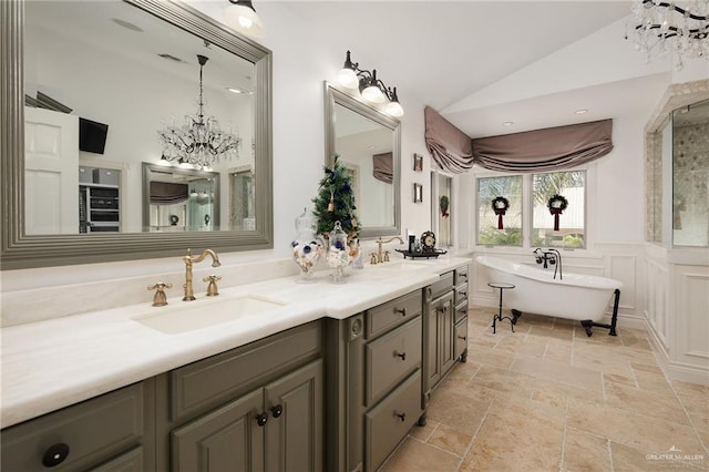 bathroom with a washtub, vanity, vaulted ceiling, and a notable chandelier