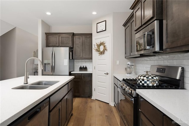 kitchen with tasteful backsplash, dark brown cabinetry, stainless steel appliances, sink, and hardwood / wood-style floors