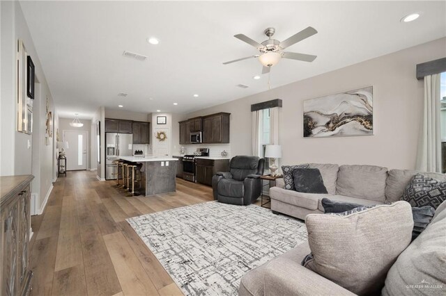 living room with ceiling fan and light hardwood / wood-style flooring