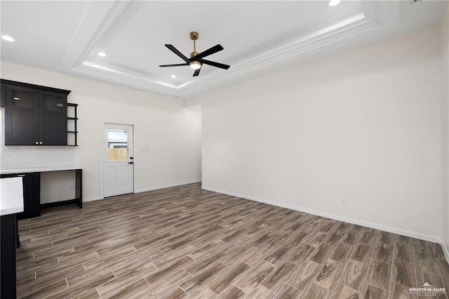 unfurnished living room featuring a tray ceiling, ceiling fan, and dark wood-type flooring