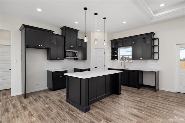 kitchen with pendant lighting, a center island, light hardwood / wood-style floors, and sink