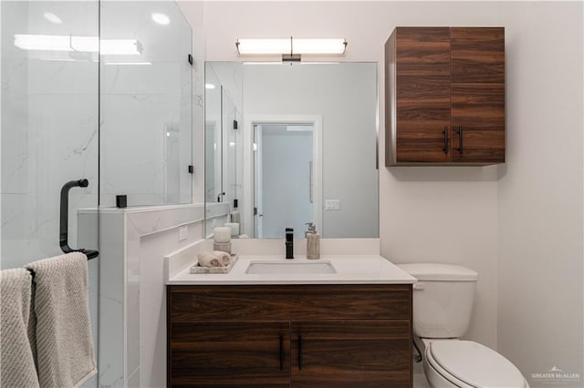 bathroom featuring a shower with door, vanity, and toilet