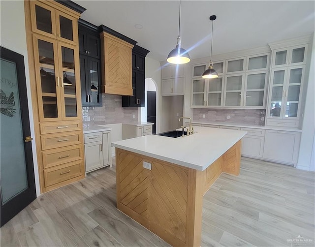 kitchen with white cabinets, sink, a kitchen island with sink, and tasteful backsplash