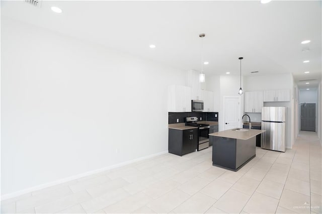 kitchen featuring a sink, white cabinets, appliances with stainless steel finishes, a center island with sink, and pendant lighting