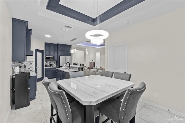 dining area featuring marble finish floor, a raised ceiling, visible vents, and baseboards