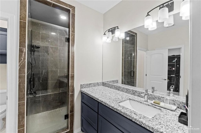 full bathroom featuring toilet, a stall shower, a walk in closet, and vanity