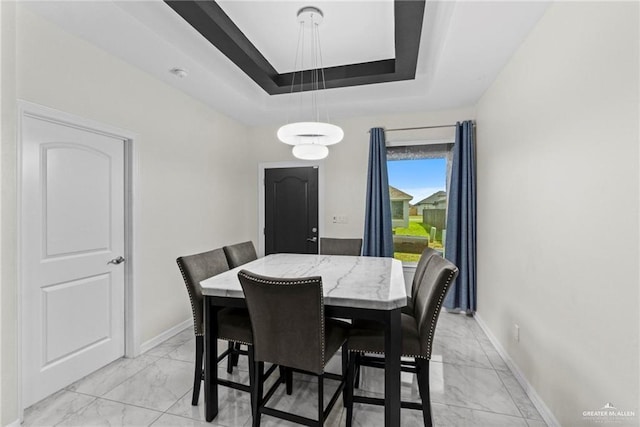 dining room featuring marble finish floor, baseboards, and a raised ceiling