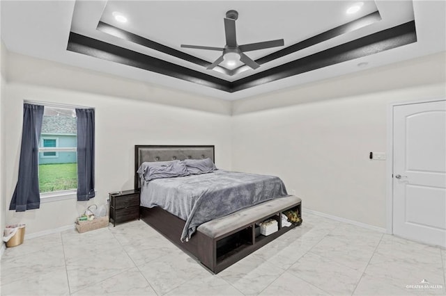 bedroom featuring a raised ceiling, marble finish floor, and baseboards