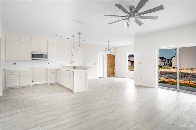 2609 E Solar Dr, Mission, TX 78574 - kitchen featuring stainless steel microwave, open floor plan, a peninsula, and light wood-style flooring