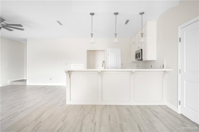 2609 E Solar Dr, Mission, TX 78574 - kitchen featuring stainless steel microwave, light countertops, a peninsula, a ceiling fan, and white cabinetry
