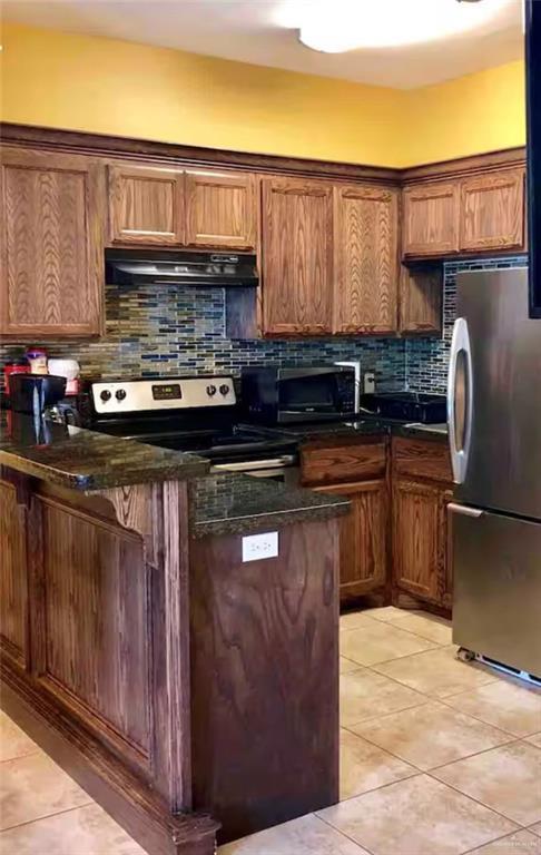 107 E Pike St, South Padre Island, TX 78597 - kitchen featuring light tile patterned flooring, stainless steel appliances, tasteful backsplash, and exhaust hood