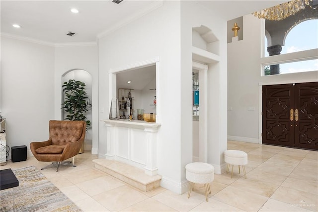 entrance foyer with crown molding, a towering ceiling, and light tile patterned flooring