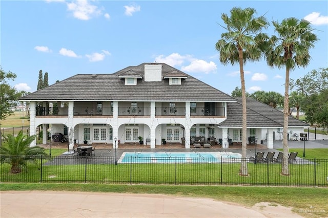 back of house with a patio, a fenced in pool, a balcony, and a lawn