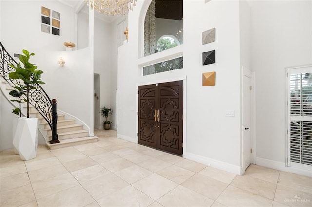 tiled entryway with a towering ceiling and a notable chandelier