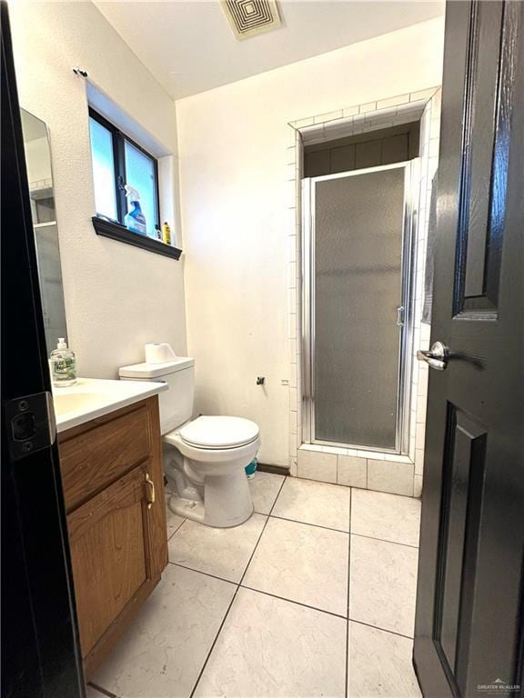 bathroom featuring tile patterned flooring, vanity, toilet, and walk in shower