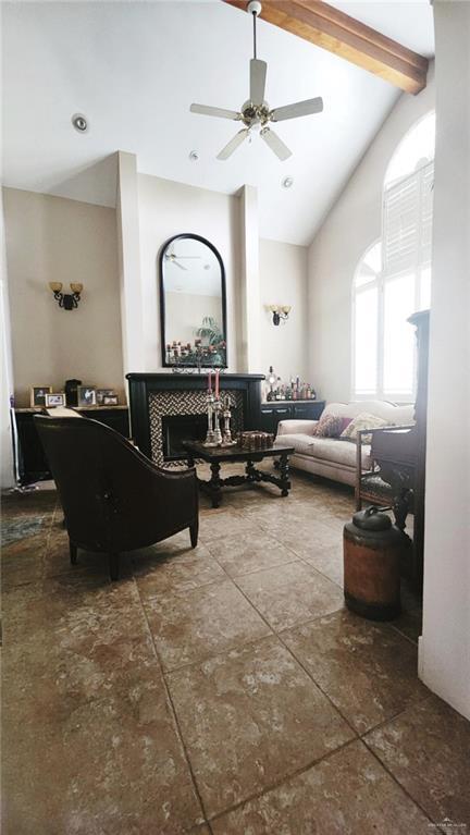 living room with beamed ceiling, ceiling fan, and high vaulted ceiling