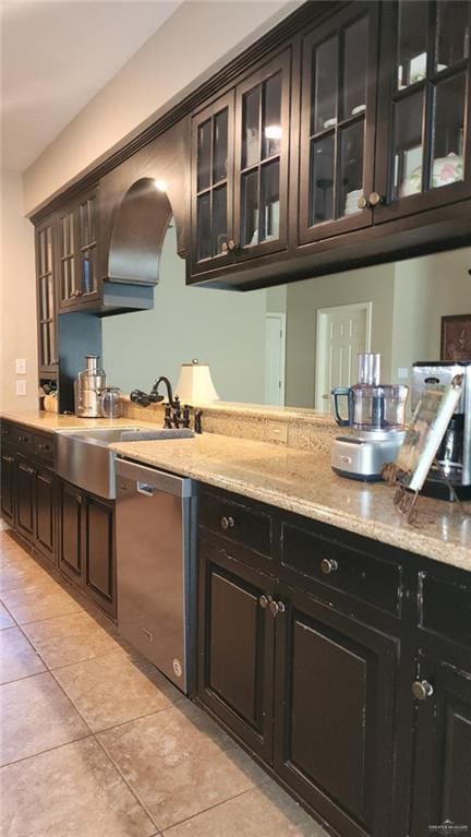 bar with sink, light tile patterned floors, dishwasher, dark brown cabinets, and light stone countertops