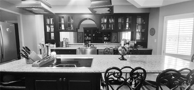 kitchen with light stone counters, black electric stovetop, plenty of natural light, and sink