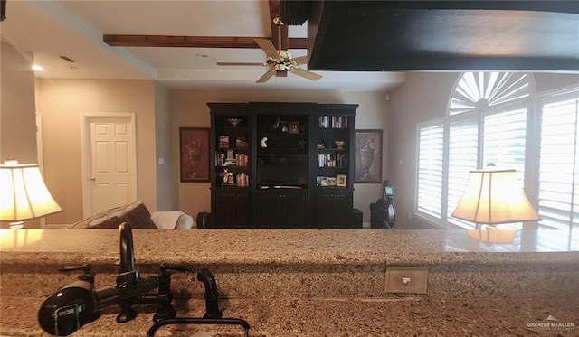 interior space with light stone counters, beamed ceiling, and ceiling fan