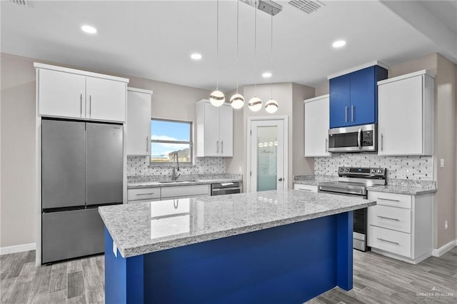 kitchen featuring decorative light fixtures, white cabinetry, sink, and appliances with stainless steel finishes