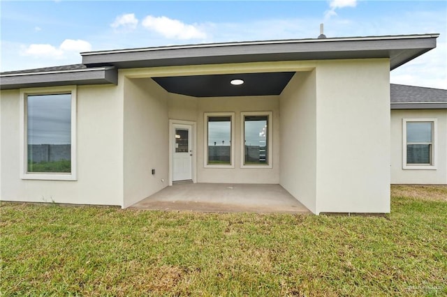 entrance to property with a patio and a lawn