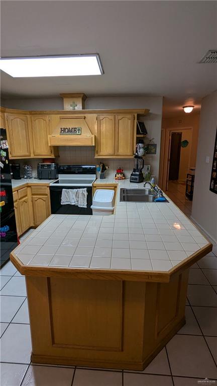 kitchen with tile counters, sink, white range with electric cooktop, light tile patterned flooring, and custom range hood