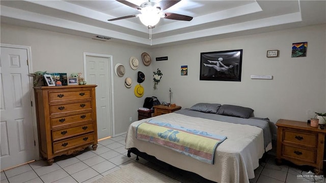 tiled bedroom with a raised ceiling and ceiling fan