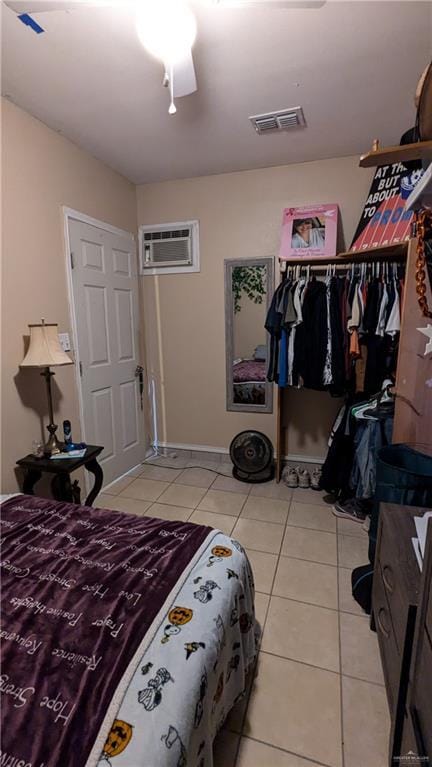 bedroom with ceiling fan, light tile patterned flooring, and a wall mounted air conditioner