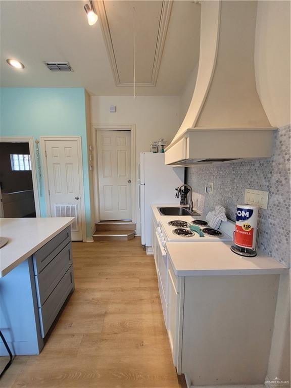 kitchen featuring sink, custom exhaust hood, light wood-type flooring, gray cabinetry, and tasteful backsplash