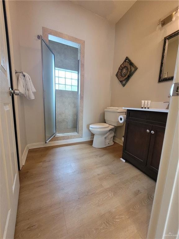 bathroom featuring wood-type flooring, vanity, an enclosed shower, and toilet