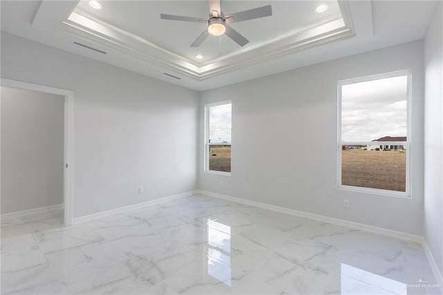 empty room featuring ceiling fan and a raised ceiling