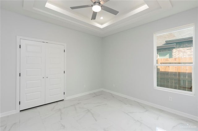 unfurnished room featuring a raised ceiling and ceiling fan