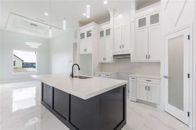 kitchen with white cabinetry, sink, pendant lighting, and a kitchen island with sink