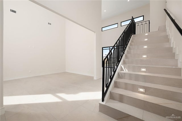 staircase with tile patterned flooring and a high ceiling