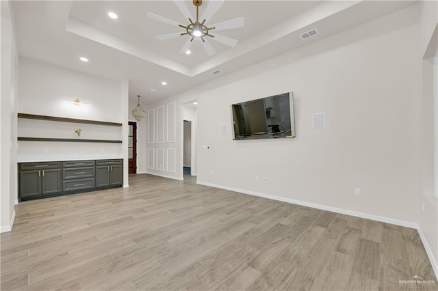 unfurnished living room featuring recessed lighting, a raised ceiling, visible vents, and light wood finished floors