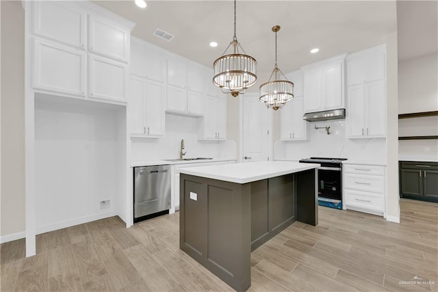 kitchen featuring visible vents, white cabinets, a center island, stainless steel appliances, and light countertops