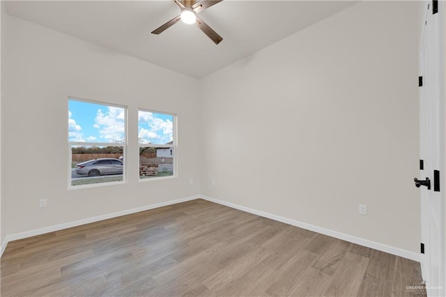 spare room featuring light wood finished floors, a ceiling fan, and baseboards