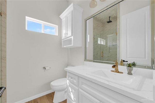 full bathroom with a marble finish shower, toilet, vanity, wood finished floors, and baseboards