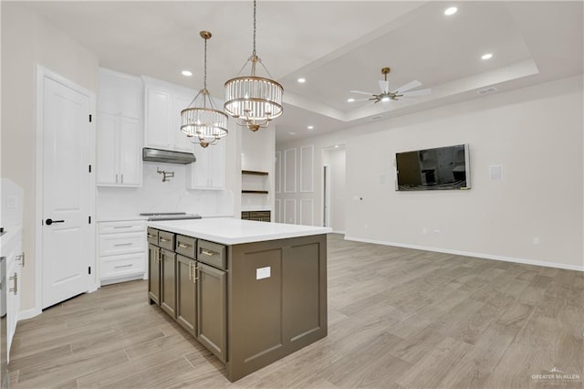 kitchen featuring a center island, decorative light fixtures, light countertops, open floor plan, and white cabinets