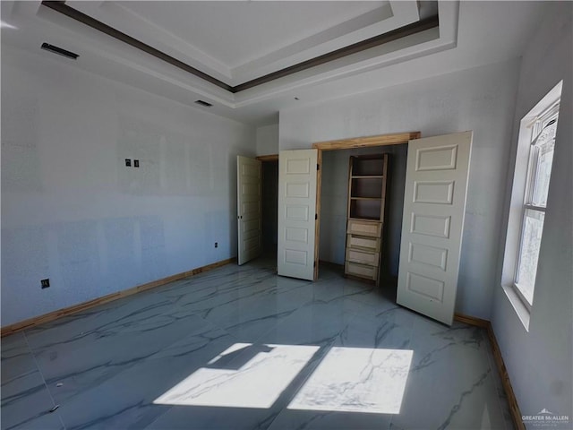 unfurnished bedroom with marble finish floor, baseboards, and a tray ceiling