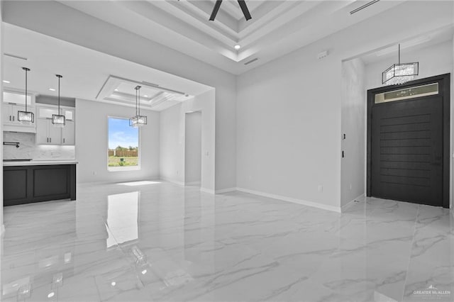 interior space with marble finish floor, a raised ceiling, and baseboards