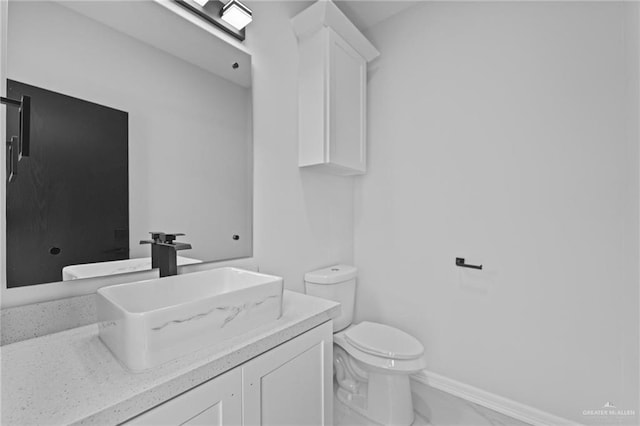 bathroom featuring toilet, marble finish floor, baseboards, and vanity