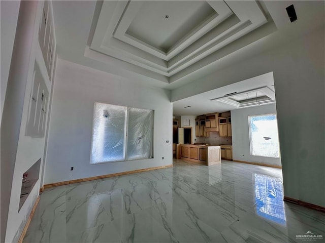 unfurnished living room featuring marble finish floor, a raised ceiling, and baseboards